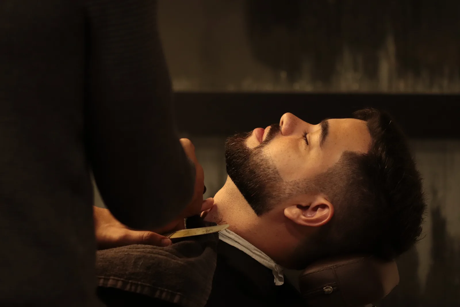 Barbeiro fazendo acabamento de barba com navalha na MYL Barber Clinic