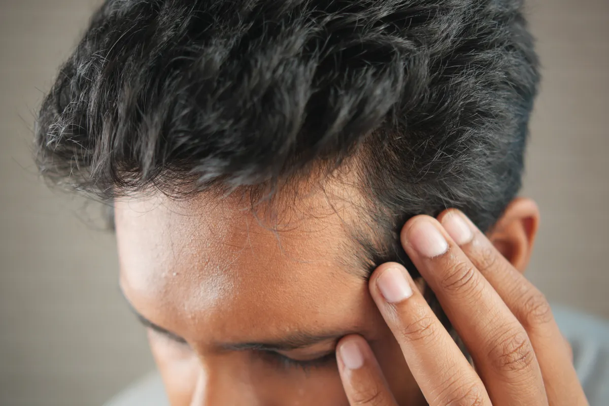 Homem observando a linha do cabelo com a mão